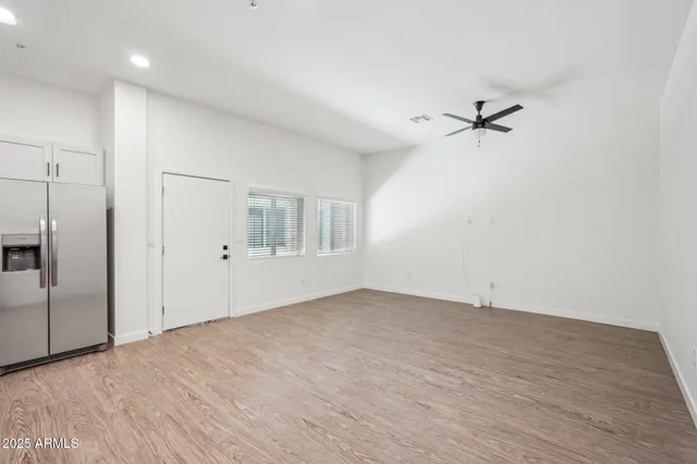 a view of empty room with wooden floor and fan