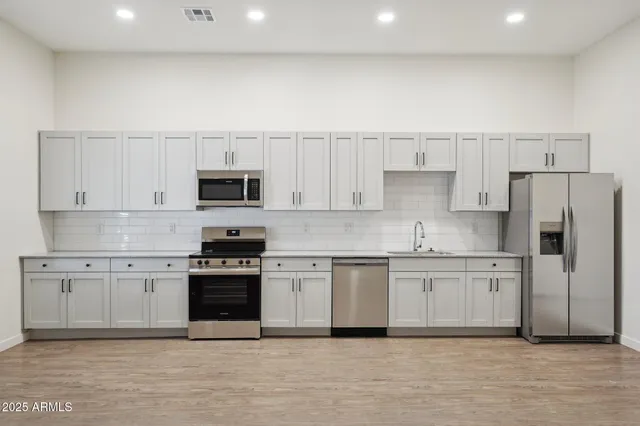 a kitchen with white cabinets and stainless steel appliances