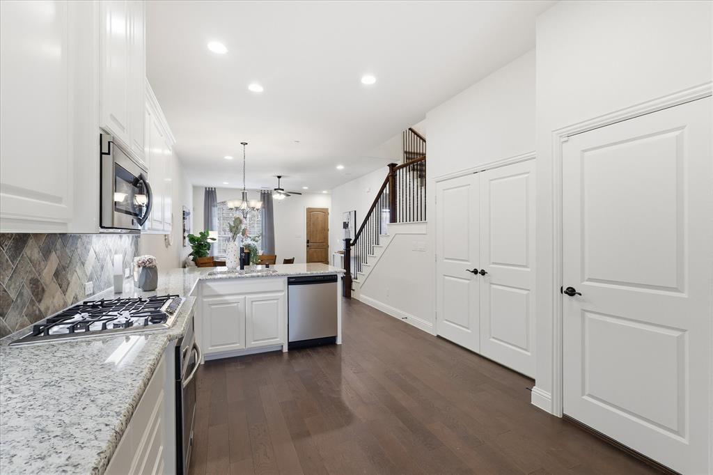 4642 Rhett Lane, Unit B Carrollton, TX 75010 - Photo 17 of 26 Kitchen with a peninsula, white cabinets, light stone countertops, a chandelier, and decorative backsplash
