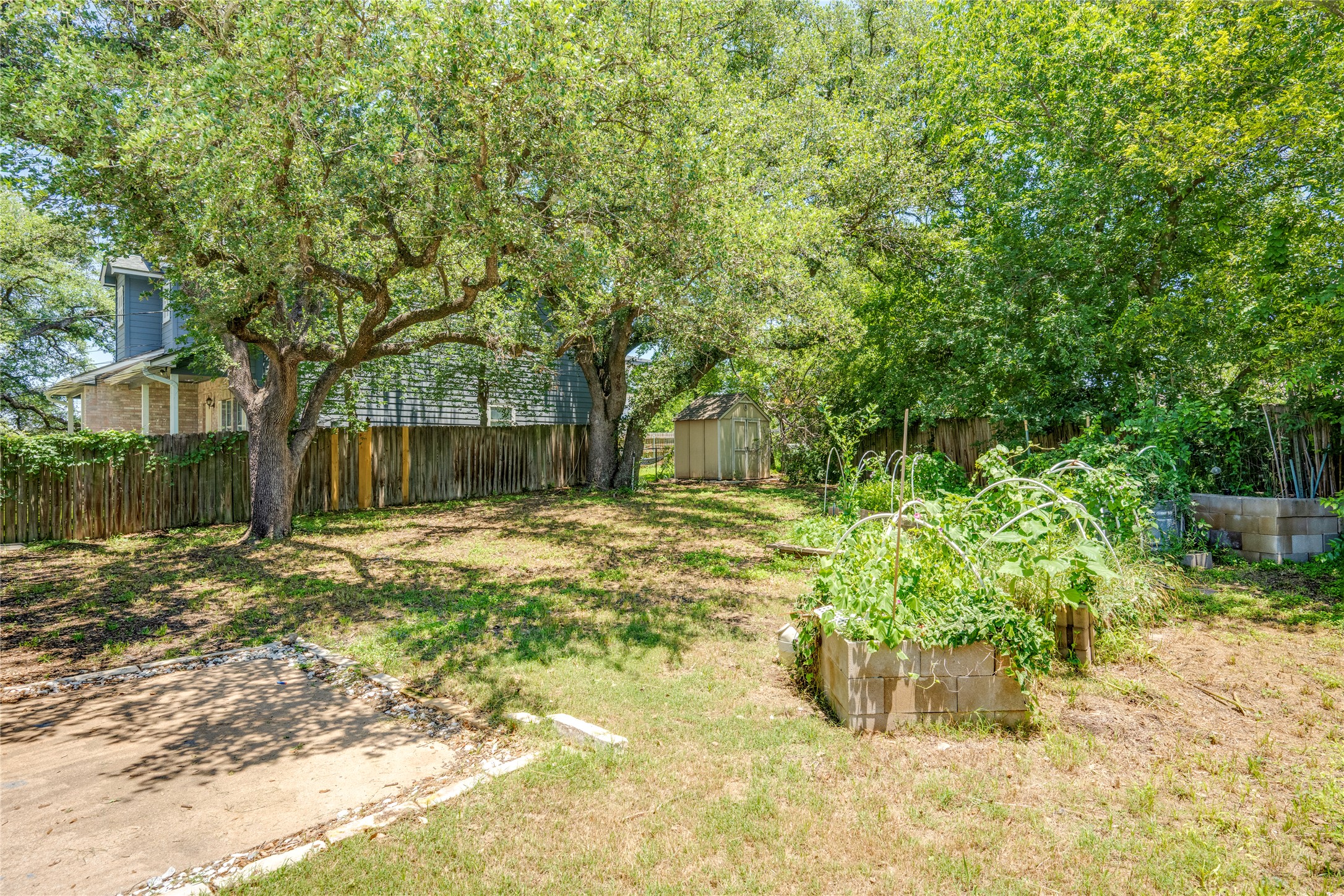 1707 Overhill Drive Austin, TX 78721 - Photo 31 of 36 Mature trees shade this spacious yard, featuring a garden bed and a storage shed, enclosed by a privacy fence.