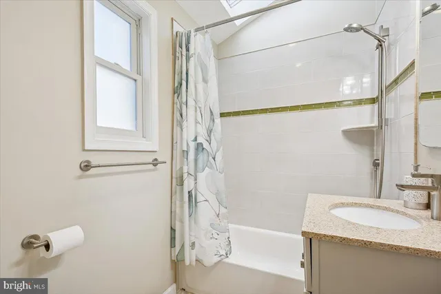 a bathroom with a granite countertop sink a mirror and a bathtub