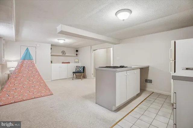 a view of kitchen with refrigerator and white cabinets