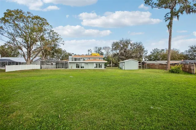 a view of a house with a big yard and large trees