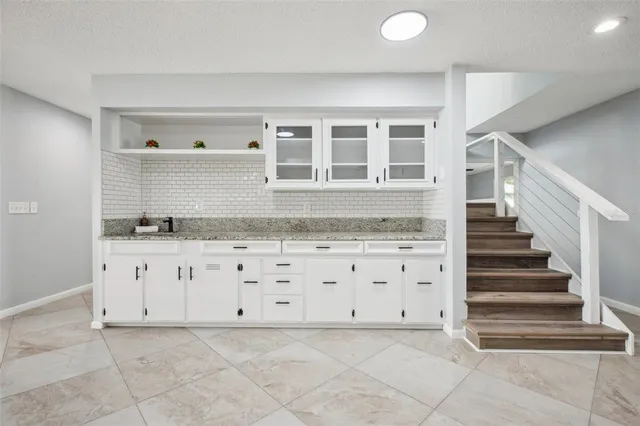a kitchen with granite countertop white cabinets and a sink