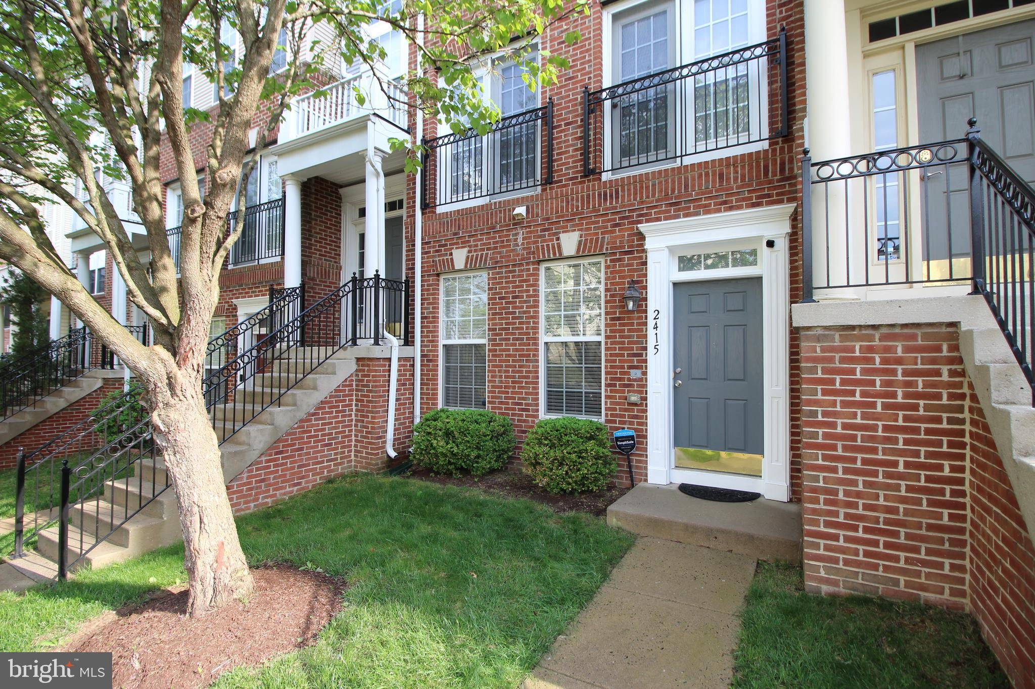 a view of a brick house with a yard and large trees