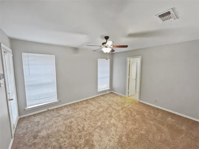 a view of an empty room and chandelier fan