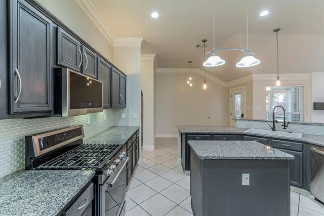 a kitchen with granite countertop a sink a counter space appliances and cabinets