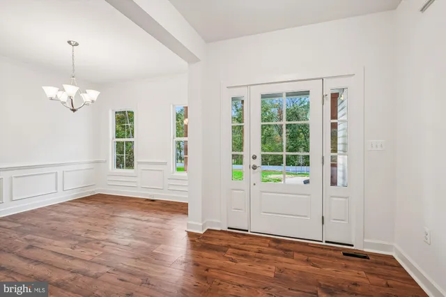 an empty room with wooden floor mirror and windows