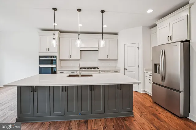 a kitchen with kitchen island granite countertop a sink a center island stainless steel appliances and cabinets