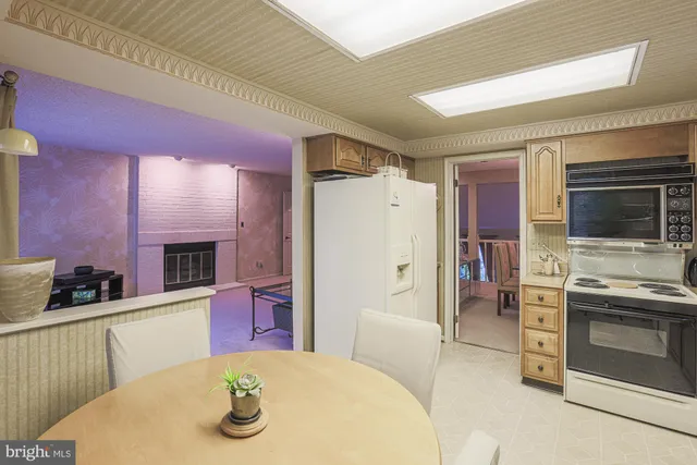 a kitchen with stainless steel appliances kitchen island granite countertop a refrigerator a stove a microwave oven with white cabinets and wooden floor