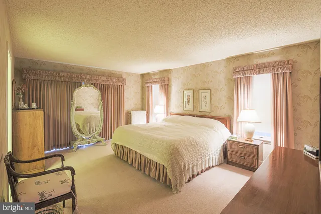 a spacious bedroom with a bed a mirror and windows