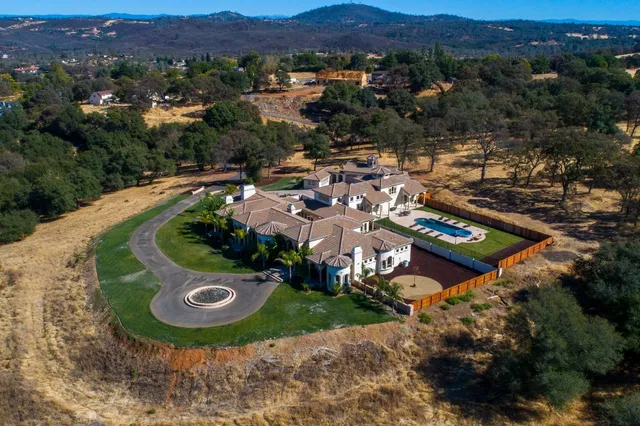 a view of a lush green outdoor space with a swimming pool and valleys in the background