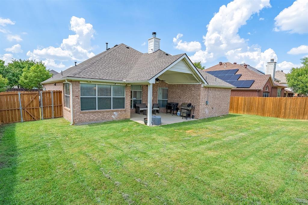 2609 Cowboy Trail Little Elm, TX 75068 - Photo 32 of 34 Back of property with roof with shingles, brick siding, a patio area, a fenced backyard, and a chimney
