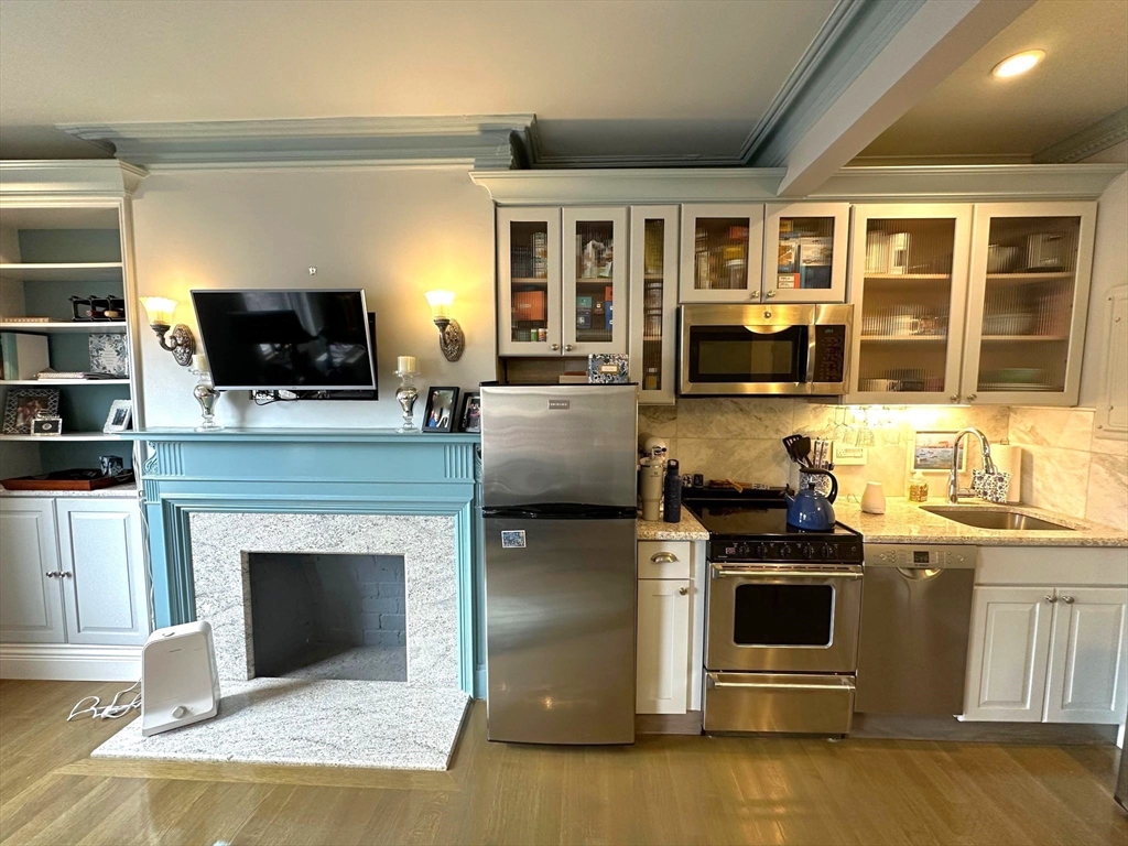 88 Charles Street, Unit 5 Boston, MA 02114 - Photo 3 of 15 a kitchen with stainless steel appliances granite countertop a stove top oven a sink dishwasher a refrigerator and a microwave with wooden floor