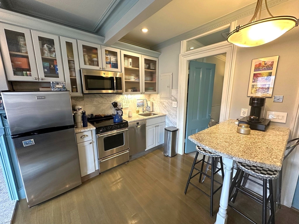 88 Charles Street, Unit 5 Boston, MA 02114 - Photo 4 of 15 a kitchen with stainless steel appliances granite countertop a stove top oven a sink a dining table and chairs
