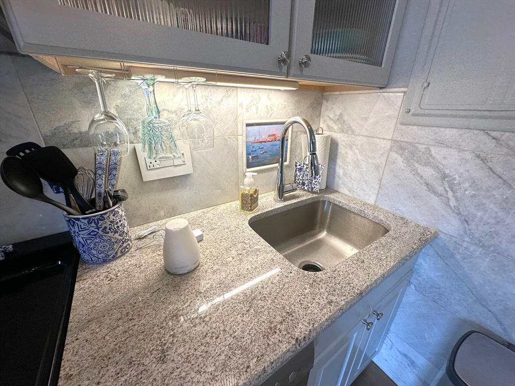 88 Charles Street, Unit 5 Boston, MA 02114 - Photo 8 of 15 a kitchen with granite countertop a sink a stove and a wooden floor