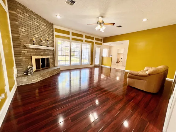 a view of a livingroom with furniture wooden floor a fireplace and windows