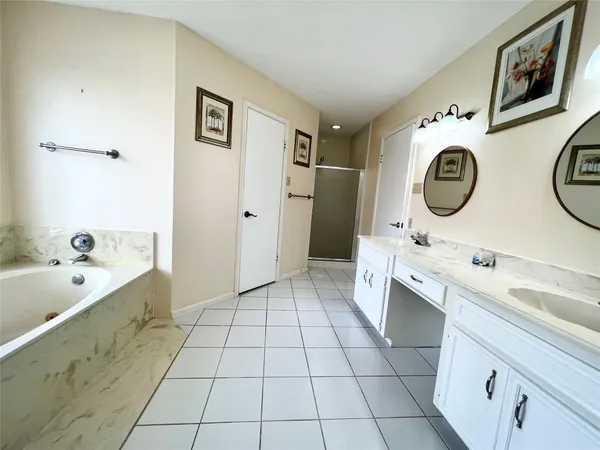 a spacious bathroom with a double vanity sink mirror and bathtub