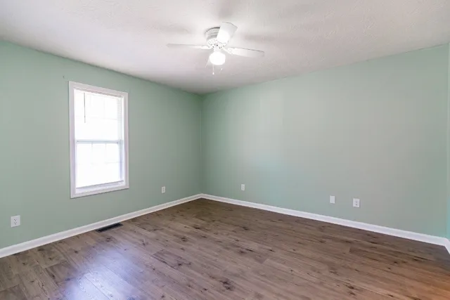 an empty room with wooden floor closet and windows
