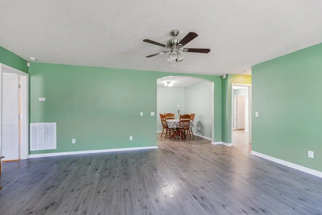 a view of a room with wooden floor a ceiling fan and windows