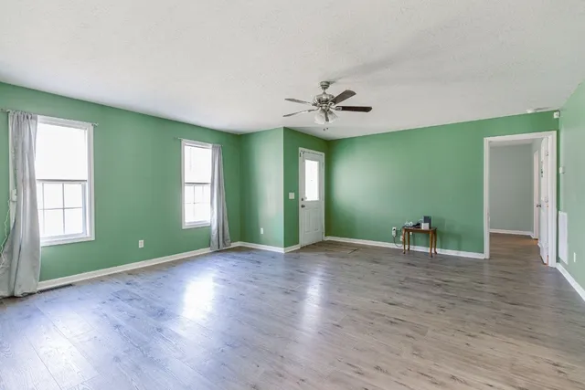 a view of an empty room with window and wooden floor