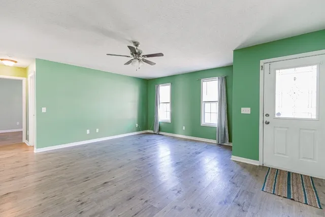 a view of an empty room with window and wooden floor