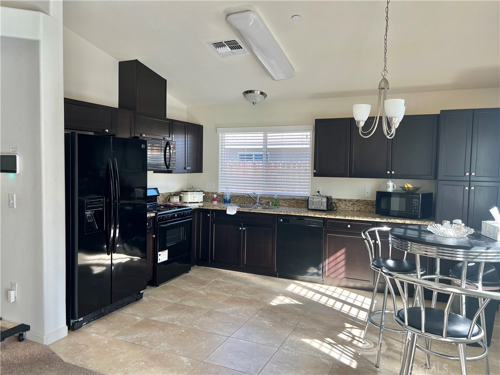 2185 Drake Avenue Merced, CA 95348 - Photo 7 of 34 a kitchen with stainless steel appliances granite countertop a refrigerator a sink dishwasher a stove and a dining table with wooden floor