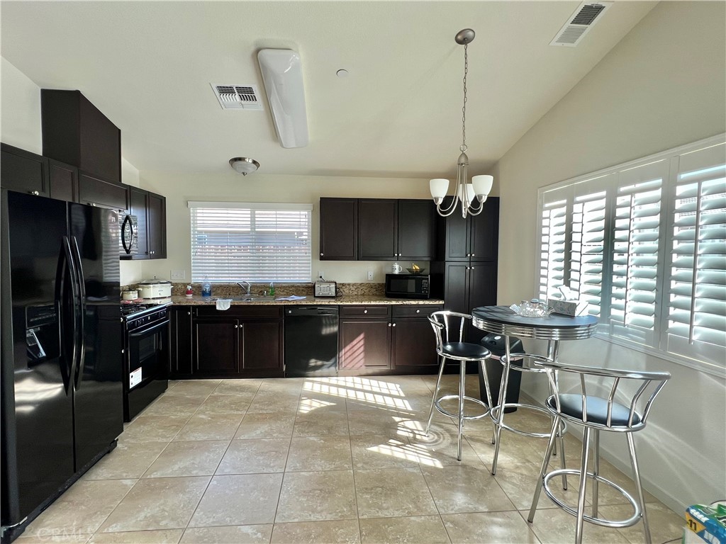 2185 Drake Avenue Merced, CA 95348 - Photo 9 of 34 a kitchen with a chandelier a kitchen island a stove and a refrigerator