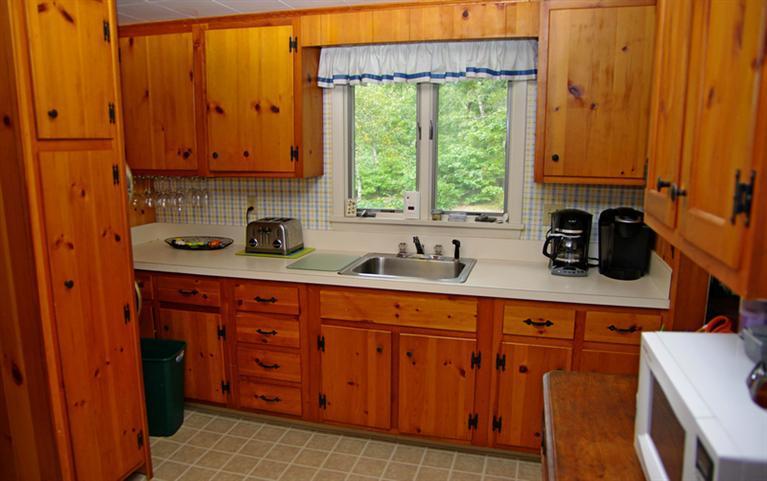 169 Foster Road Brewster, MA 02631 - Photo 10 of 14 a kitchen with stainless steel appliances granite countertop wooden cabinets a sink and a window