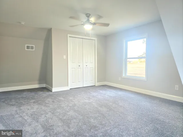 an empty room with a window and a ceiling fan