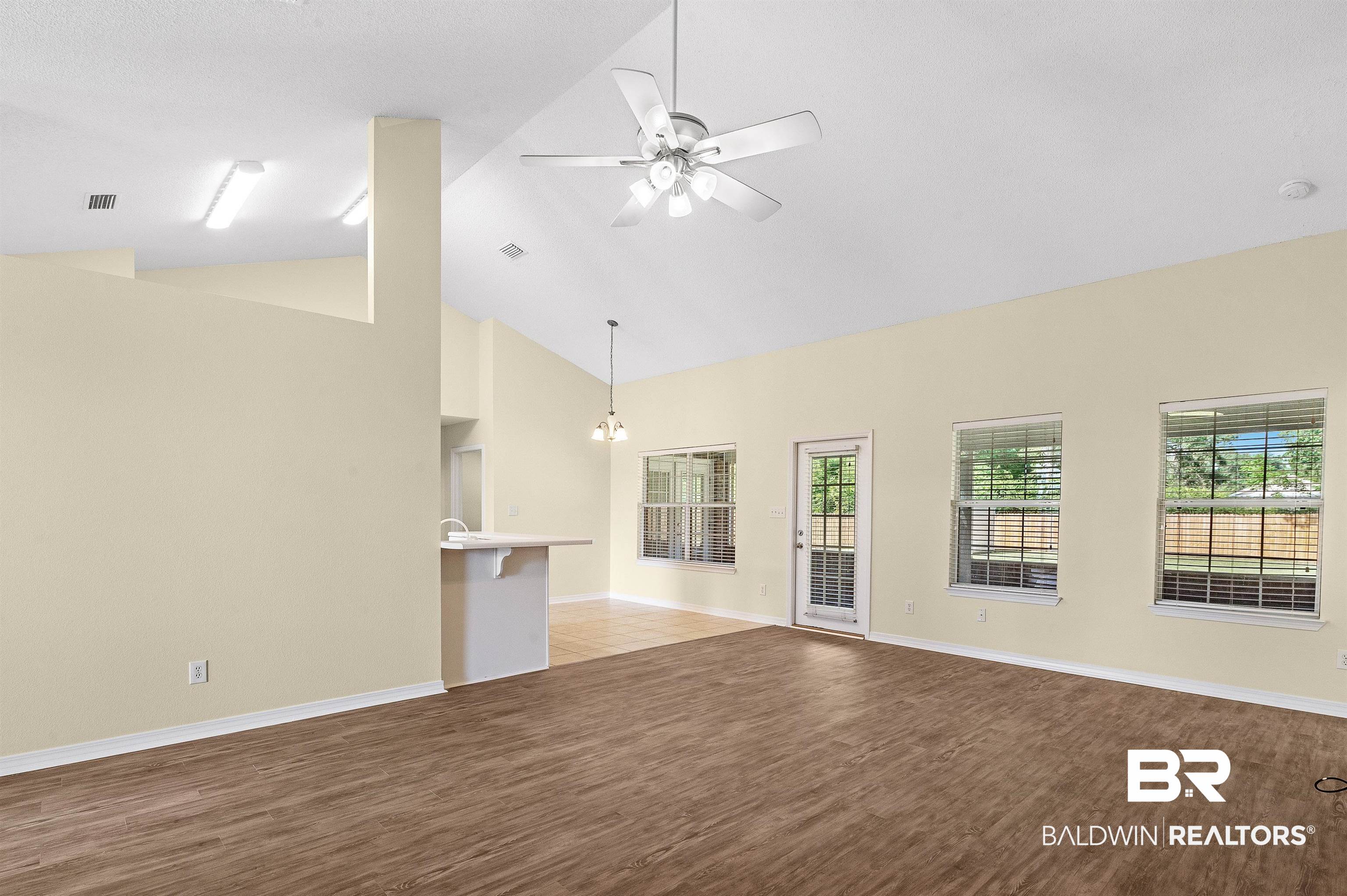12443 Venice Boulevard Foley, AL 36535 - Photo 23 of 59 Unfurnished living room with ceiling fan with notable chandelier, high vaulted ceiling, and hardwood / wood-style flooring