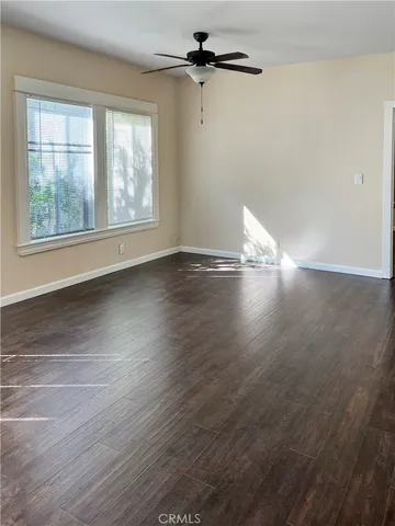 an empty room with wooden floor chandelier fan and windows
