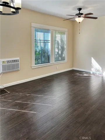 an empty room with wooden floor chandelier fan and windows