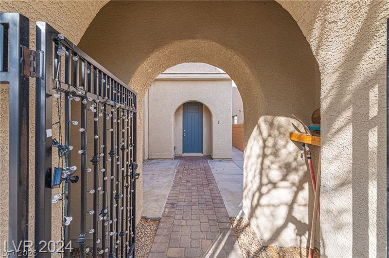 9056 Tony Ridge Avenue Las Vegas, NV 89148 - Photo 2 of 32 Beyond the wrought iron entry, a charming arched walkway leads to the main entrance.