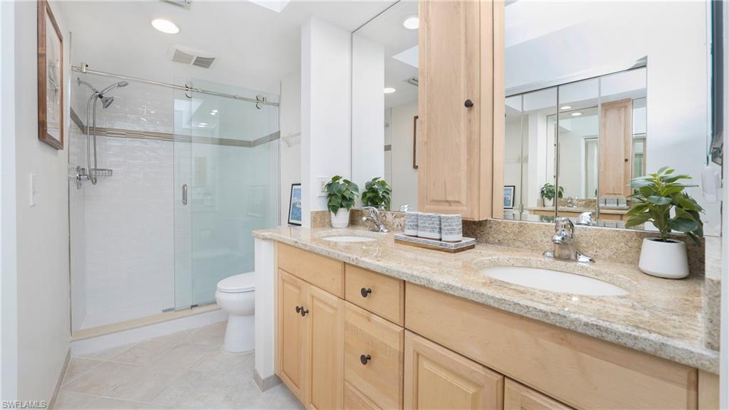 4957 Pepper Circle, Unit C104 Naples, FL 34113 - Photo 11 of 22 a bathroom with a granite countertop sink a toilet and a mirror