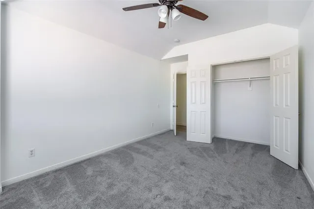 an empty room with a ceiling fan and carpet