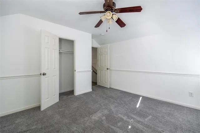 an empty room with closet and a ceiling fan