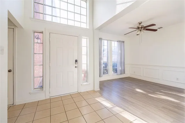 a view of an empty room with window and chandelier fan