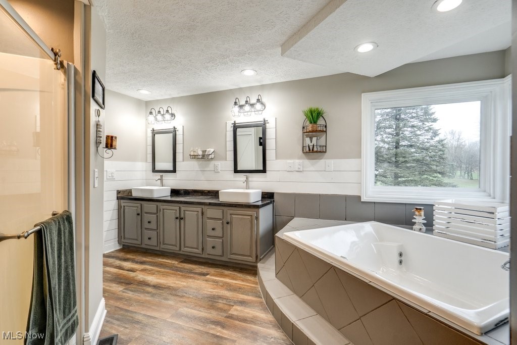4121 New Milford Road Rootstown, OH 44272 - Photo 40 of 50 Bathroom featuring a bath, a textured ceiling, a sink, and wood finished floors