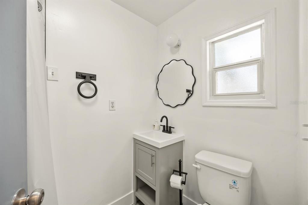 31300 Highway 441 Okeechobee, FL 34972 - Photo 21 of 33 a bathroom with a toilet a sink a mirror and a window