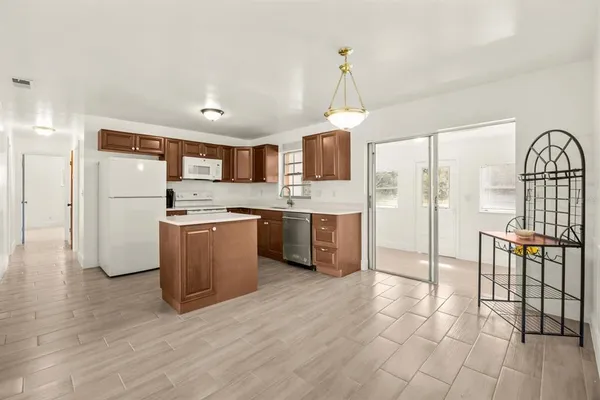 a kitchen with stainless steel appliances a refrigerator a stove a sink a dining table and chairs with wooden floor