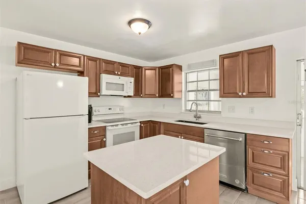 a white kitchen with sink stove and refrigerator