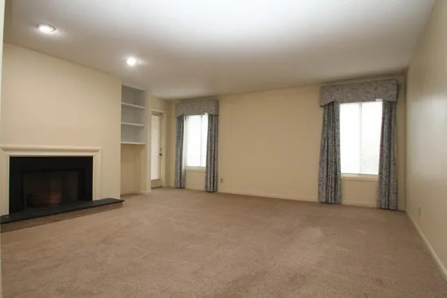 an empty room with windows and fireplace