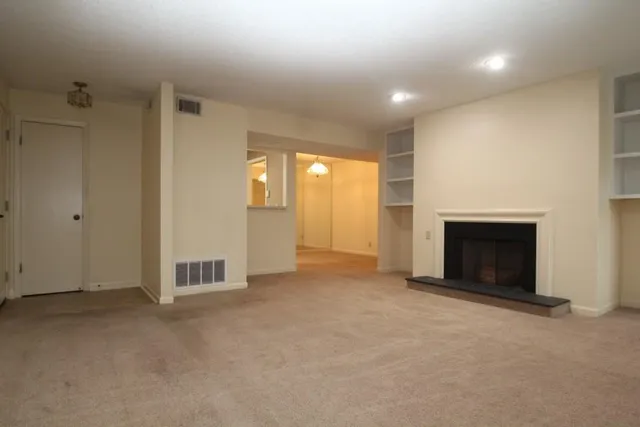 an empty room with a fireplace and natural light