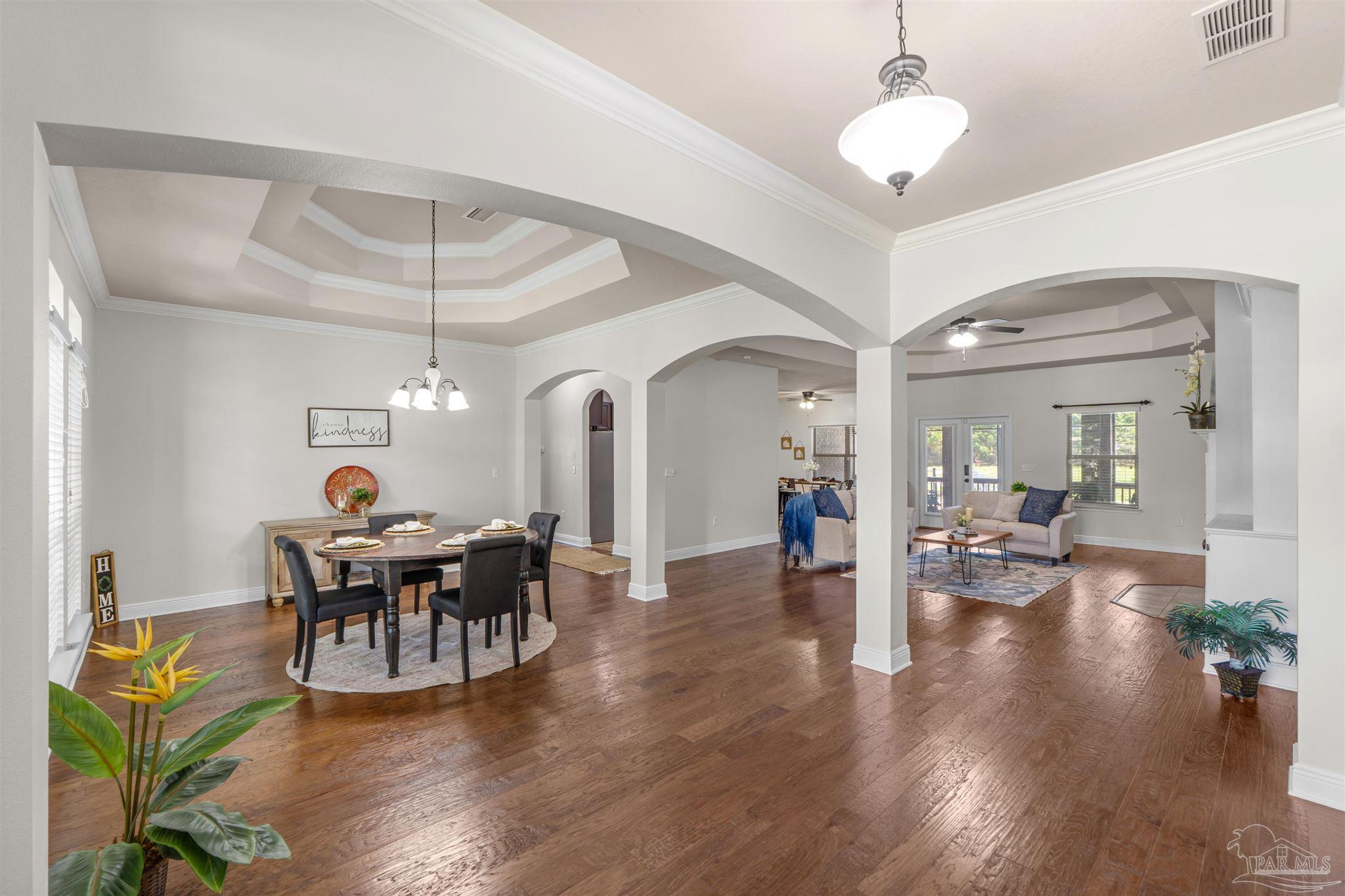 2698 Tulip Hill Road Pace, FL 32571 - Photo 3 of 65 a dining room with wooden floor a chandelier a wooden table and chairs