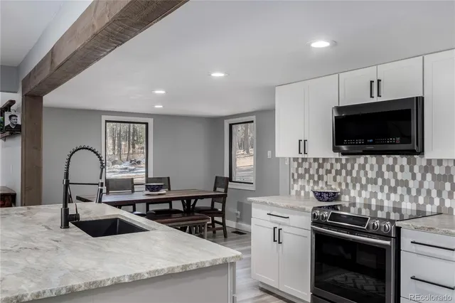 a kitchen with stainless steel appliances granite countertop a sink and a stove top oven with wooden floor