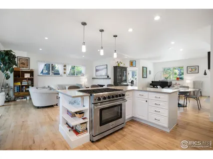 a kitchen with stainless steel appliances a stove a sink a oven a dining table with wooden floor