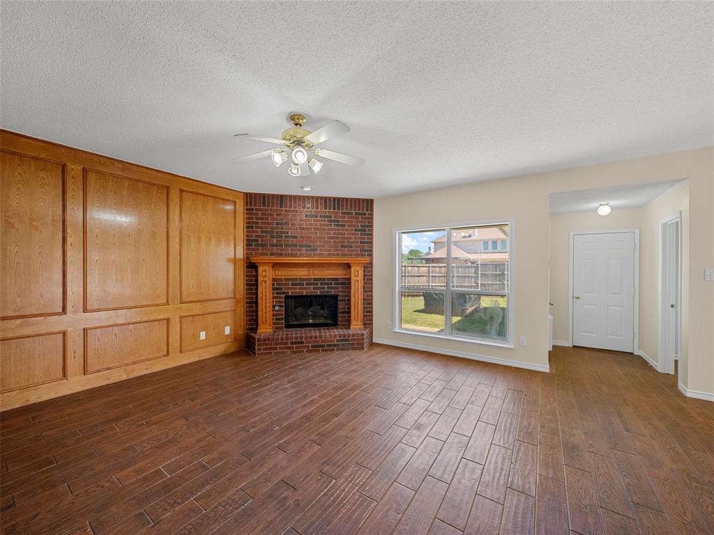 741 Aspen Court Allen, TX 75002 - Photo 26 of 40 Downstairs living room featuring wood tiled floors, ceiling fan, a brick fireplace, and a decorative wall