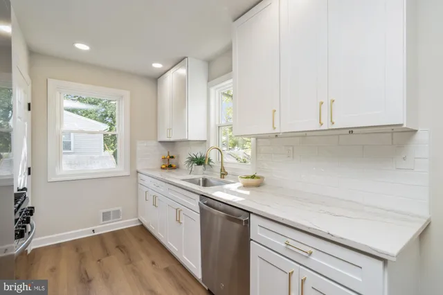 a kitchen with a sink dishwasher window and cabinets