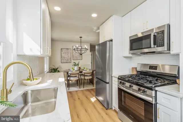 a kitchen with stainless steel appliances a stove a refrigerator a sink a stove and cabinets